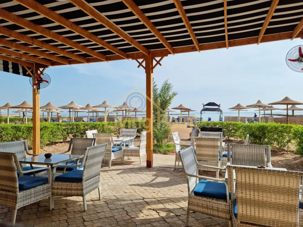 Erschwingliche Strandwohnung mit schattiger Resortterrasse, Korbstühlen und Meerblick